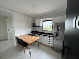 a kitchen with a wooden table and a refrigerator at Flat Bugayalê Lounge in Garanhuns