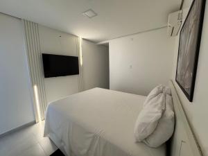 a bedroom with a white bed and a television at Flat Bugayalê Lounge in Garanhuns