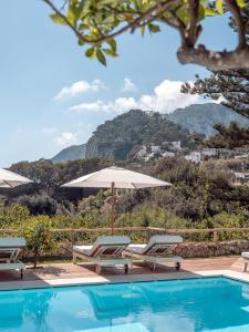 a swimming pool with two lounge chairs and an umbrella at Hotel La Minerva in Capri