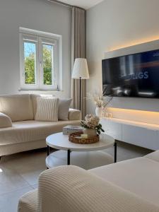 a living room with a couch and a tv at Lūm Posidonia in Posidhonía