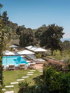 a swimming pool with umbrellas and lounge chairs next to it at Hotel La Minerva in Capri