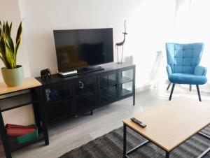 a living room with a television and a blue chair at Caldasia in Caldas de Reis