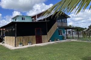a house with a black roof and a green at Casa HerShei in Orange Walk