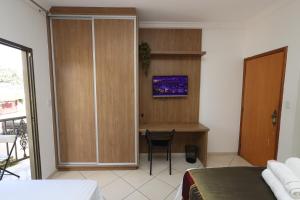 a bedroom with a bed and a desk with a tv at Pousada House Garden in Goiânia