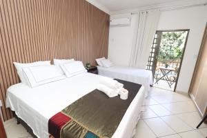 a hotel room with two beds and a balcony at Pousada House Garden in Goiânia