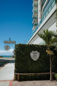 a hedge sign in front of a building with a palm tree at Hotel da Praia in Vila Velha