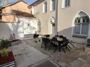 a patio with a table and chairs in front of a house at TEMPLE JACQUESSON - Gare - Centre ville - WIFI RAPIDE et STREAMING - PARKING GRATUIT - CHECK IN 24H - CLIMATISATION - IDEAL PROS - cour privée - barbecue in Chalons en Champagne
