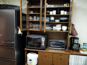a kitchen with a microwave and a refrigerator at Cozy Koharuka in Shima