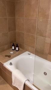 a bathroom with a bath tub with two bottles of soap at Altos Ushuaia Hotel & Resto in Ushuaia +59 photos