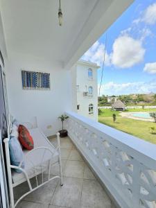 a balcony with a white chair and a large window at Malindi Getaway, Near Beach in Malindi