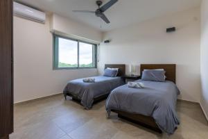 two beds in a room with a window at La Poza Suites in Isla Mujeres +32 photos