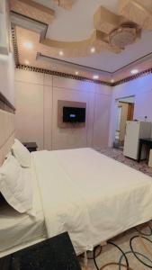 a large white bed in a room with a tv at شقق مخدومه in Najran +2 photos