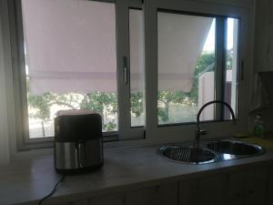 a kitchen counter with a sink and two windows at Natalia's Serene Hub in Egina +28 photos