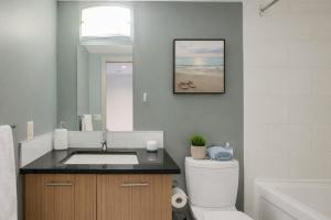 a bathroom with a sink and a toilet and a mirror at Chic & Modern Apartment In The Heart Of Downtown in Victoria