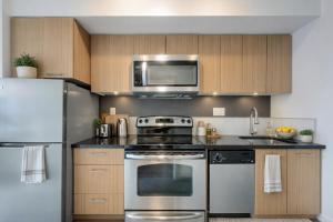 a kitchen with a stainless steel stove and a microwave at Chic & Modern Apartment In The Heart Of Downtown in Victoria