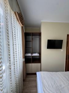 a bedroom with a bed and a tv on a wall at Ивелия Къща за гости in Dospat