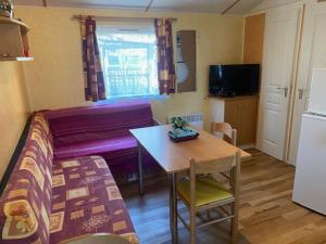 a small room with a bed and a table and a kitchen at Mobile home Besse in Besse-et-Saint-Anastaise