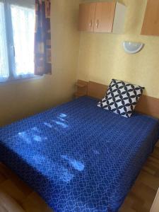 a small bedroom with a blue bed with a pillow at Mobile home Besse in Besse-et-Saint-Anastaise +11 photos