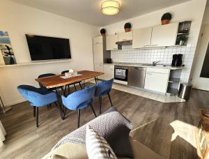 a kitchen and dining room with a table and blue chairs at FeWo "Seebär" Whg2 in Dahme