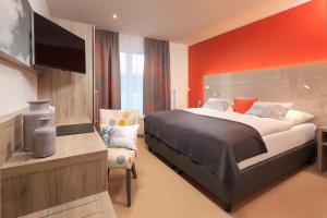 a bedroom with a large bed with an orange wall at Allgäu Art Hotel in Kempten