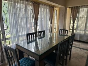a dining room with a table and chairs and windows at Raaha Residency in Mysore