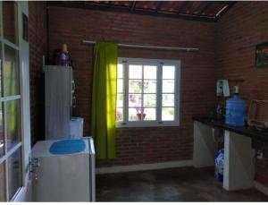 a kitchen with a refrigerator and a window at Chalé Guaíras in Mulungu