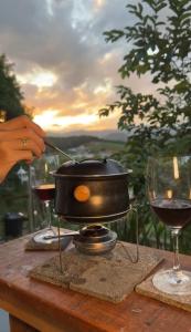 a pot on a table with two glasses of wine at Luz de Cabana in Santo Amaro da Imperatriz