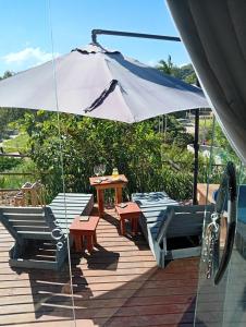 a table and chairs and an umbrella on a deck at Luz de Cabana in Santo Amaro da Imperatriz