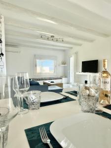 a white table with a plate and glasses on it at Villa Greystone & Sky Mykonos in Tourlos