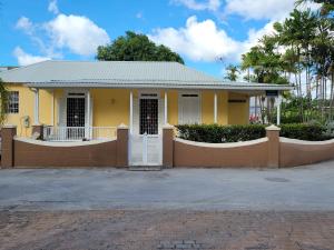 a yellow house with a gate in front of it at Clariston in Bridgetown
