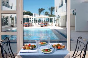 a table with two plates of food next to a pool at Swiss Wellness Hotel Suites in Hurghada