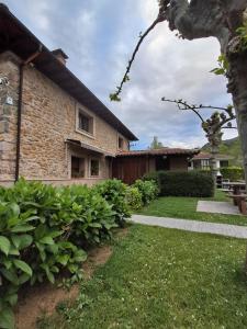 a house with a grass yard and a building at La orilla del sella in Cangas de Onís
