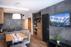 a kitchen with a table and a tv on a wall at CASA IBEX - Residence Veronza con piscina, Dolomiti Affitti in Cavalese