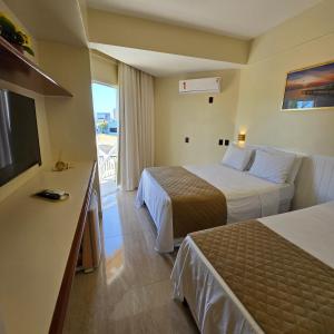 a hotel room with two beds and a flat screen tv at Jatobá Praia Hotel in Aracaju +78 photos