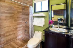 a bathroom with a toilet and a sink and a mirror at Villa Kiskadee - Beautiful Mountain Views with Private Pool in Quepos