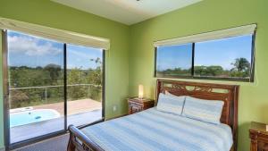 a bedroom with a bed and a large window with a tub at Villa Kiskadee - Beautiful Mountain Views with Private Pool in Quepos