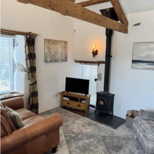 a living room with a couch and a stove at Nuthatch Cottage in Cardinham