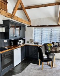a kitchen with black cabinets and a table at Nuthatch Cottage in Cardinham +10 photos