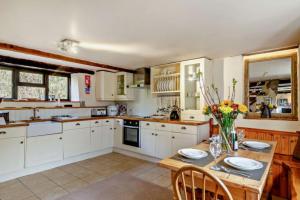 a kitchen with white cabinets and a table with flowers on it at Tawnawood in Cardinham