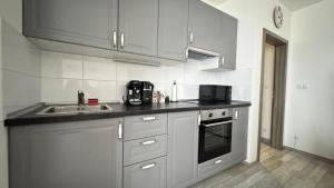 a kitchen with white cabinets and a sink and a microwave at THE RIVERSIDE APARTMENT with Balcony in Prague +3 photos