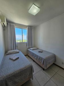 two beds in a room with a window at Apto.napraia BEACH 901 em Piçarras com vista mar in Piçarras +40 photos