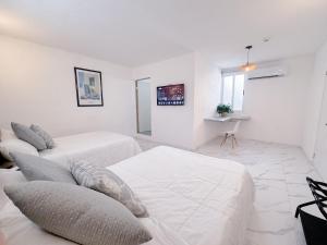 a white room with two beds and a couch at Downtown Suites - Hotel Boutique by Maraf in Cancún