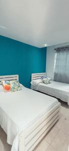 three beds in a room with a blue wall at Hostal Casa del Palmar in Santa Marta