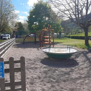 a playground in a park next to a fence at camping sous le moulin in Condes