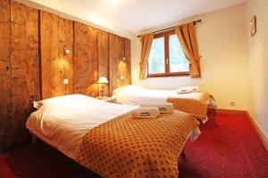 una camera d'albergo con due letti e una finestra di La Ferme des Praz apartment - Chamonix All Year a Chamonix-Mont-Blanc