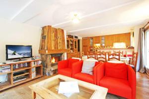 un soggiorno con 2 sedie rosse e un camino di La Ferme des Praz apartment - Chamonix All Year a Chamonix-Mont-Blanc