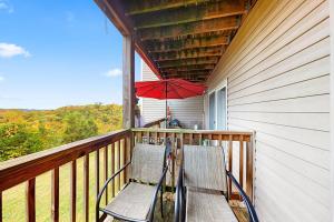 a porch with two chairs and a red umbrella at Vineyards 2909 #3 in Branson