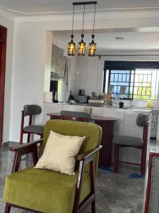 a living room with a green chair and a kitchen at Elp Living in Hoima