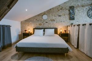 a bedroom with a large bed and a stone wall at Le Loft - Classé 5 ÉTOILES in Mussidan
