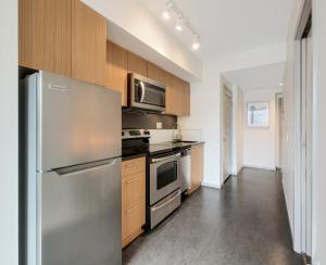 a kitchen with stainless steel appliances and wooden cabinets at Chic & Modern Apartment In The Heart Of Downtown in Victoria